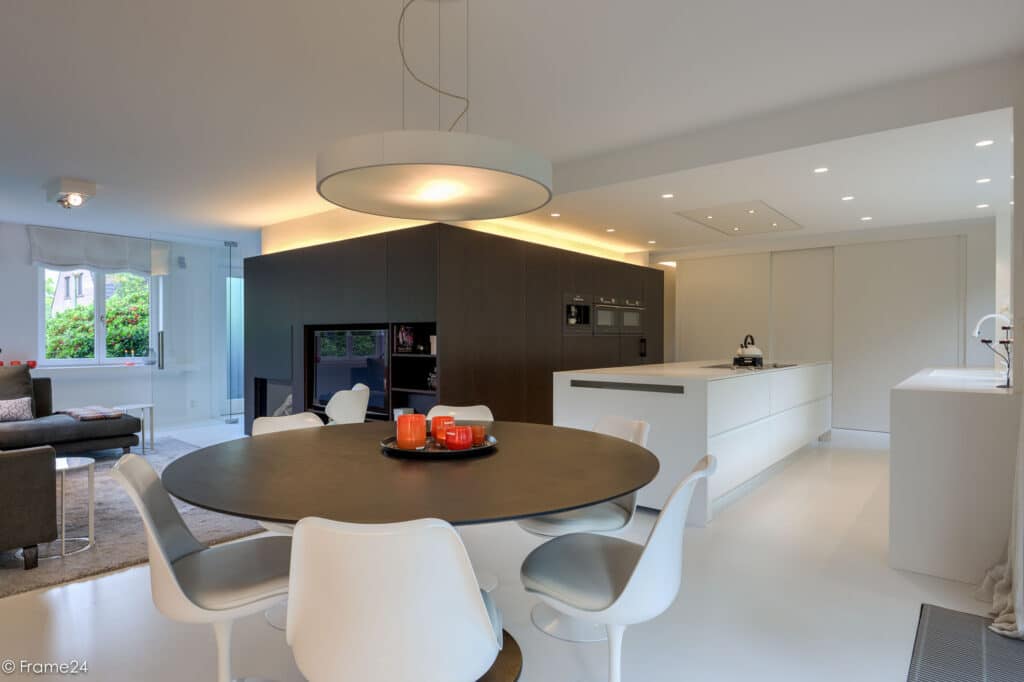 Totaaloverzicht afbeelding van dit project in Schilde. We bundelden wonen, koken en muziek rond een duidelijk middelpunt. Ontdek hoe centraal maatwerk en een naadloze vloer de woning licht en leefbaar maken.